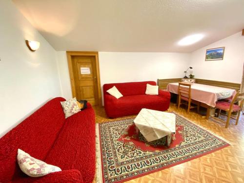 a living room with a red couch and a table at Appartamento Fodom in Arabba