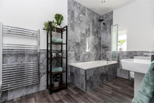uma casa de banho com uma banheira, um lavatório e um espelho. em Auckland View - a comfy & spacious 4bed with views em Coundon