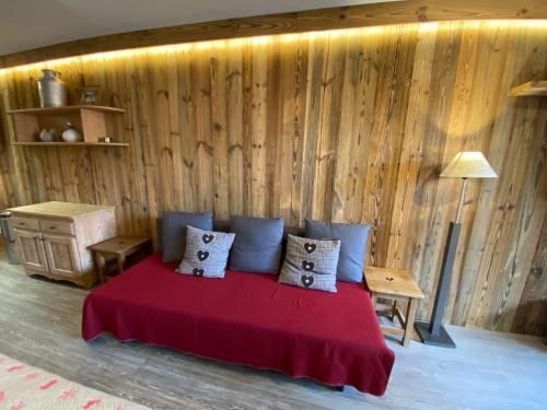 - une chambre avec un lit rouge et un mur en bois dans l'établissement Résidence CHALET DE SOLAISE - Studio 30 m2 - by MONTBLANC LODGE, à Val dʼIsère