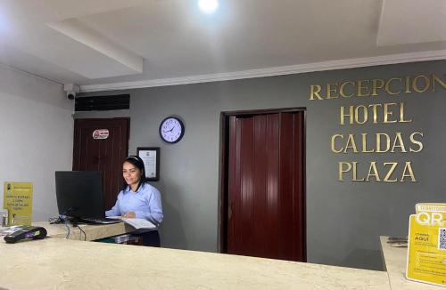 una mujer sentada en un escritorio con un portátil en Hotel Caldas Plaza, en Caldas