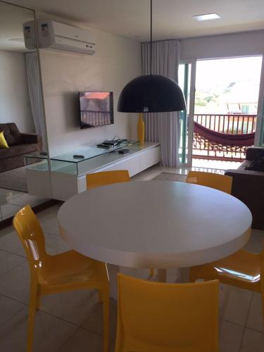 a living room with a white table and yellow chairs at Flat Club Meridional Carneiros in Tamandaré