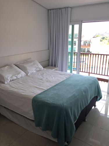 a bed in a bedroom with a large window at Flat Club Meridional Carneiros in Tamandaré