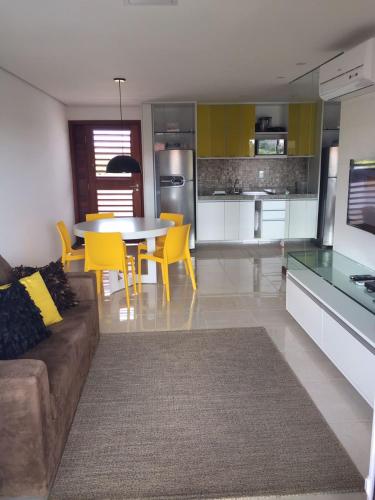 a living room and kitchen with a couch and a table at Flat Club Meridional Carneiros in Tamandaré