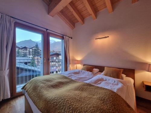 1 dormitorio con cama y ventana grande en Haus Serac en Saas-Fee