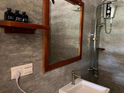 a bathroom with a sink and a mirror and a shower at Saffron Lake Yala in Tissamaharama