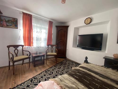 een slaapkamer met een bed en 2 stoelen en een flatscreen-tv bij Casa Cireșu in Cireşu