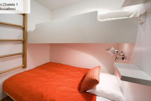 - łóżko z pomarańczową poduszką w niewielkim pokoju w obiekcie Levi Chalets w mieście Kittilä