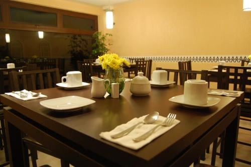 a table with plates and utensils and flowers on it at Hotel Express Alejandría in Xalapa