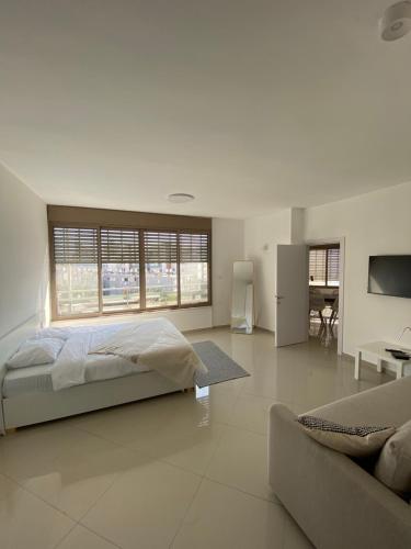 a white bedroom with a bed and a couch at Vibe Place in Netanya