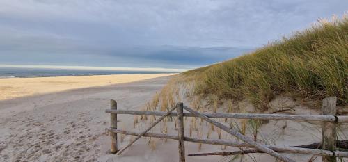 a wooden fence on the side of a sandy beach at Zakątek Ciszy. in Słuchowo