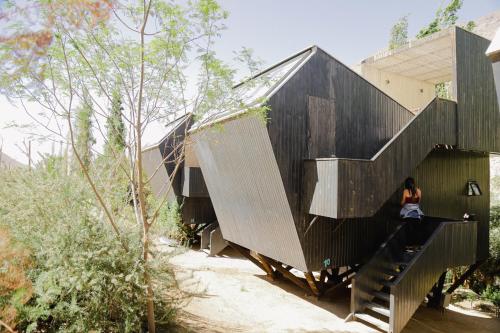 a woman sitting on the stairs of a black building at Milodge Elqui Domos in Pisco Elqui