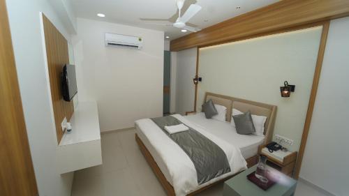 ein Schlafzimmer mit einem Bett und einem TV in der Unterkunft Hotel The Grand Crystal in Ahmedabad
