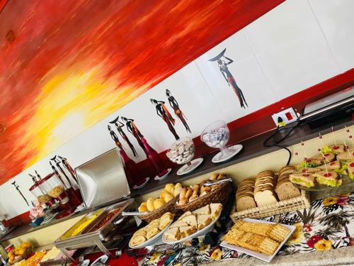 a buffet line with plates of food and bread at Hotel Rosa da Ilha Guaruja - Perto do Mar com piscina in Guarujá