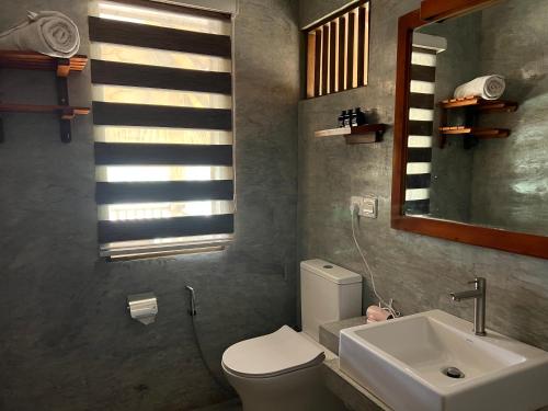 a bathroom with a toilet and a sink and a mirror at Saffron Lake Yala in Tissamaharama
