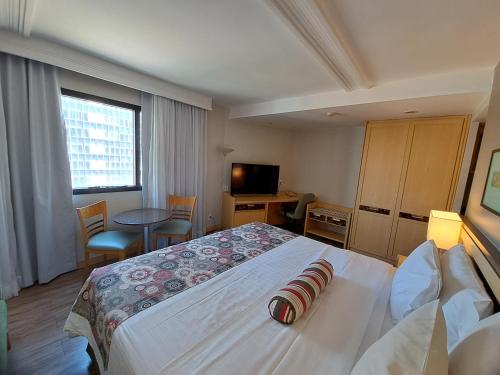 um quarto de hotel com uma cama grande e uma televisão em Flat particular no Lets Idea Brasília em Brasília