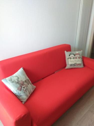 a red couch with two pillows on it at Appartamento nel Cuore della Val di Sole in Dimaro