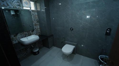 ein Badezimmer mit einem WC, einem Waschbecken und einem Spiegel in der Unterkunft Hotel The Grand Crystal in Ahmedabad