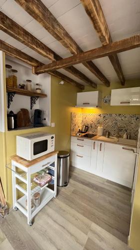 une cuisine avec des armoires blanches et un micro-ondes dans l'établissement Appartement Chalet Pra Loup, à Uvernet