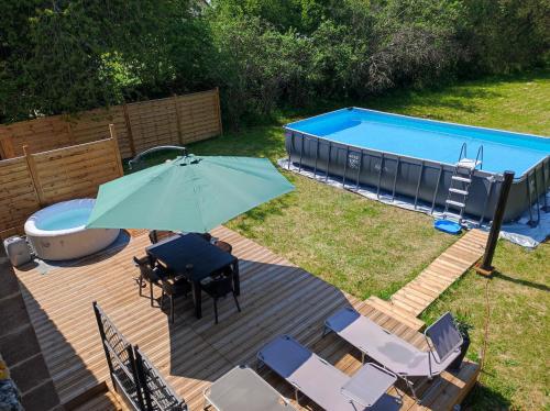 una terraza con sombrilla y sillas y una piscina en Chez l'habitant pour naturistes uniquement, nudist only, en Ville-sur-Yron
