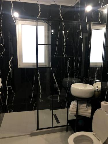 a black bathroom with a toilet and a sink at Studio cu grădina proprie in Popeşti-Leordeni