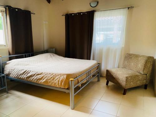 1 dormitorio con 1 cama, 1 silla y 1 ventana en Villa Mi Dushi Cas Aruba en Palm-Eagle Beach