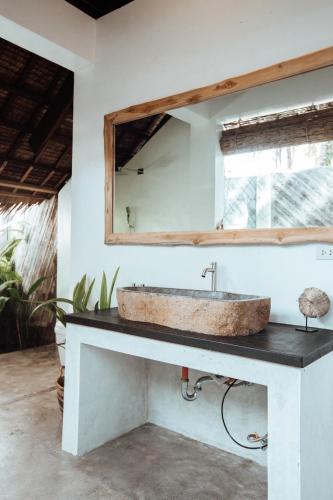 a bathroom with a stone sink and a mirror at Villa Tulua Siargao in General Luna