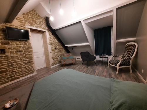 una camera da letto con un muro in pietra e un letto e sedie di la longère charmante a Céaux