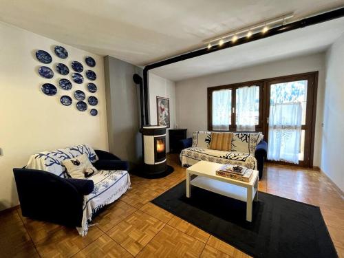 a living room with two couches and a table at Pinzolo Centro - Baita Spaziosa con Vista sui Monti in Giustino