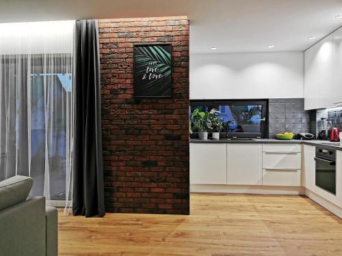 salon z ceglaną ścianą i kuchnią w obiekcie Apartament Green Plant - 2 oddzielne sypialnie, taras 30m2 i garaż podziemny w Kielcach