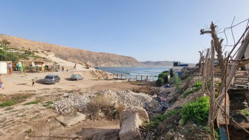 a beach with cars parked on the sand and the ocean at Good Vibes House Imsouane in Imsouane