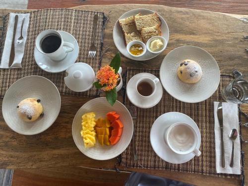 a wooden table with plates of food and cups of coffee at PINOKKIO B&B Restaurant in Jimbaran