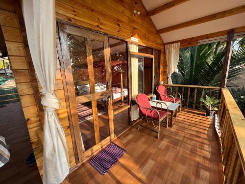 a room with a balcony with a table and chairs at Sonho do Mar in Agonda