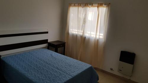 Un dormitorio con una cama azul y una ventana en don jose en Villa Gesell