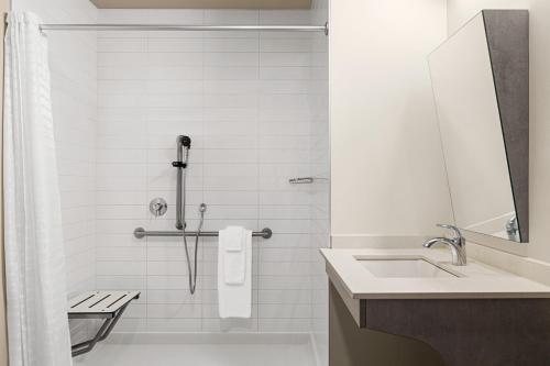 a white bathroom with a shower and a sink at Microtel Inn & Suites Dorval QC in Dorval