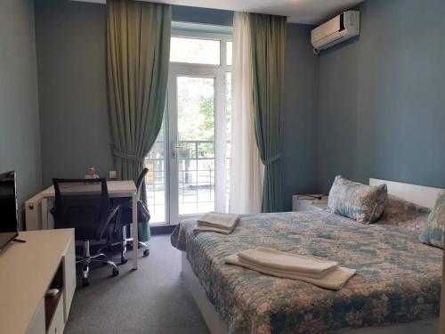a bedroom with a bed and a desk and a window at Gabala Hotel in Daşca