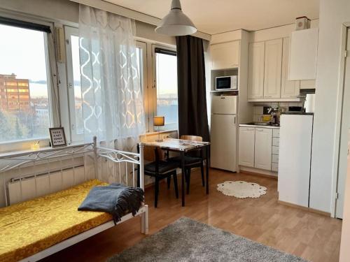 a bedroom with a table and a kitchen with a window at Apartment Kopin in Kokkola