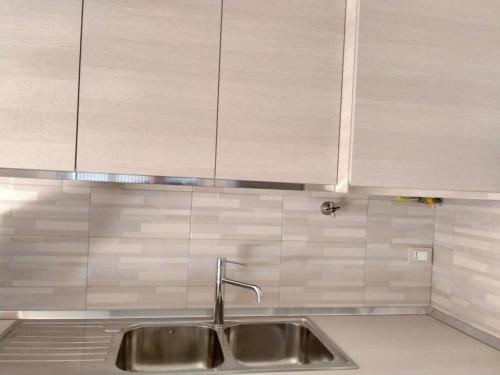 eine Küche mit einem Waschbecken und einer weiß gefliesten Wand in der Unterkunft La Casa sul Mare in Francavilla al Mare