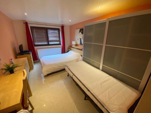 um pequeno quarto com uma cama e uma janela em Residence la Fraisiere em Bruxelas