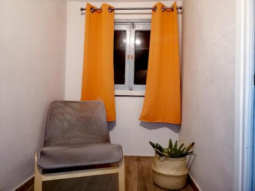 a chair in a room with orange curtains and a window at El Desván del Chisco in Cudillero
