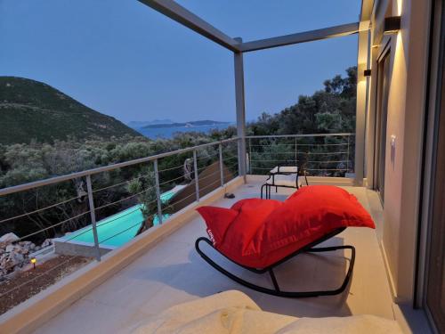 a balcony with a red pillow and a table and chairs at Villa Maya Lefkada in Évyiros