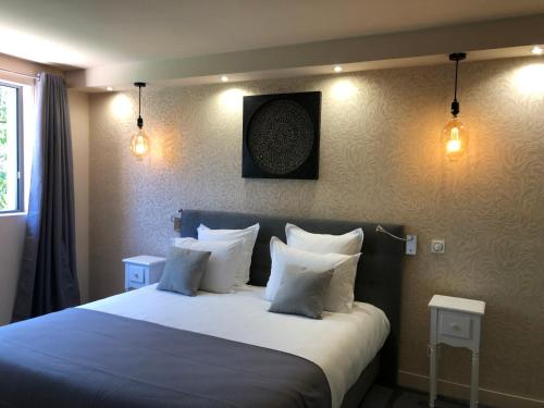 - une chambre avec un grand lit et des oreillers blancs dans l'établissement Le Parc Stanislas, à Chartres