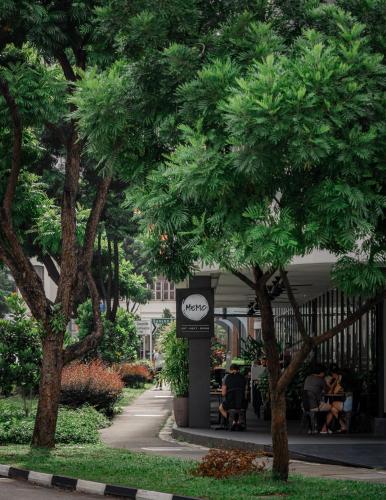 a group of people sitting at tables under trees at Studio M Hotel in Singapore
