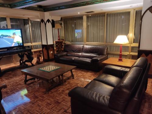 sala de estar con muebles de cuero y TV de pantalla plana en Hotel Julia, en Aranda de Duero