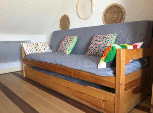 drewniana kanapa z poduszkami w pokoju w obiekcie Sables d'Or, studio 31, équipé, à 300m de la plage w mieście Frehel