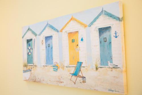 uma pintura de quatro cabanas de praia com uma cadeira em The Neuk Anstruther Sleeps 6 Fantastic Location em Anstruther