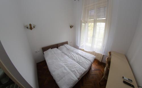 a small bed in a room with a window at Apartments & Room - Korzo in Sombor