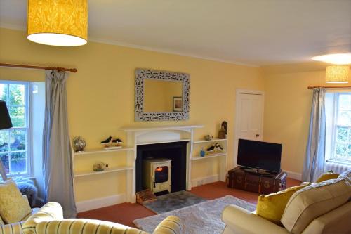 a living room with a fireplace and a tv at Creran Apartment, Kinlochlaich House in Appin