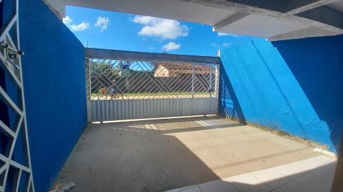 an empty room with a blue wall and a gate at Residencial Praia Quente casas in Nova Viçosa
