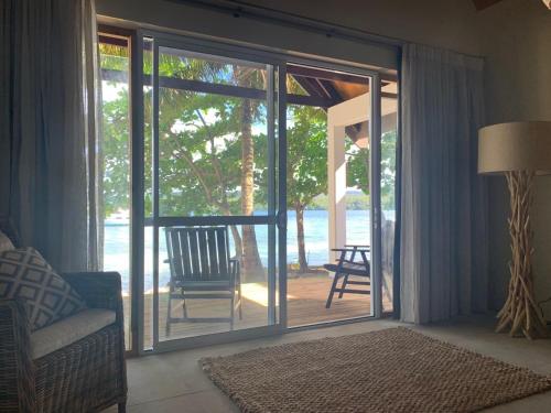 a living room with a sliding glass door with a chair at Tongan Beach Resort in Utungake
