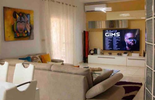 a living room with a couch and a flat screen tv at Villa Ngorè Saly in Saly Portudal